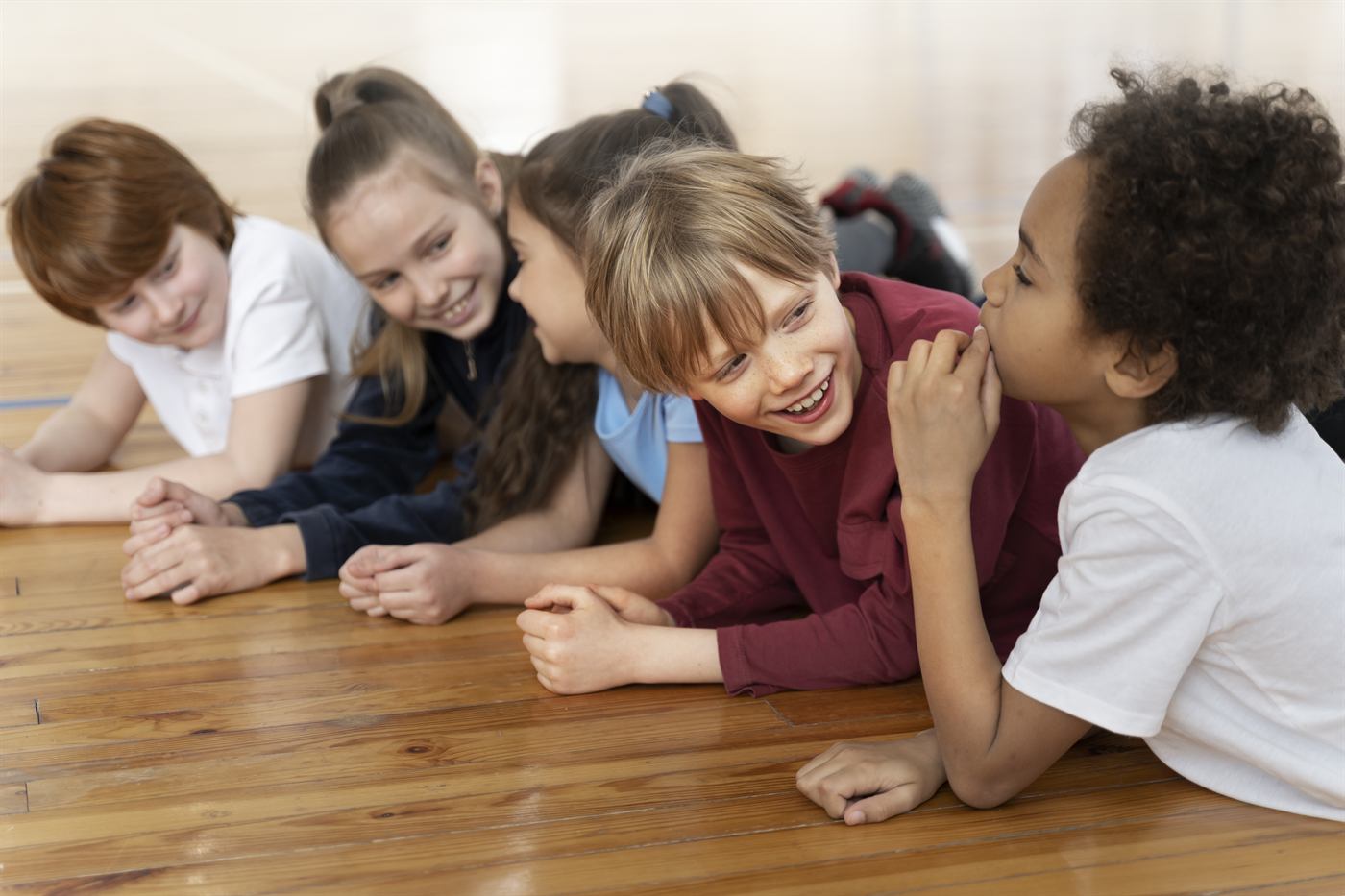 A group of smiling children lying on the floor together