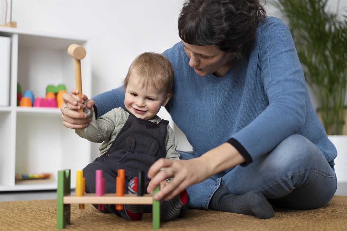 A therapist helping a toddler play with a hammer and peg toy