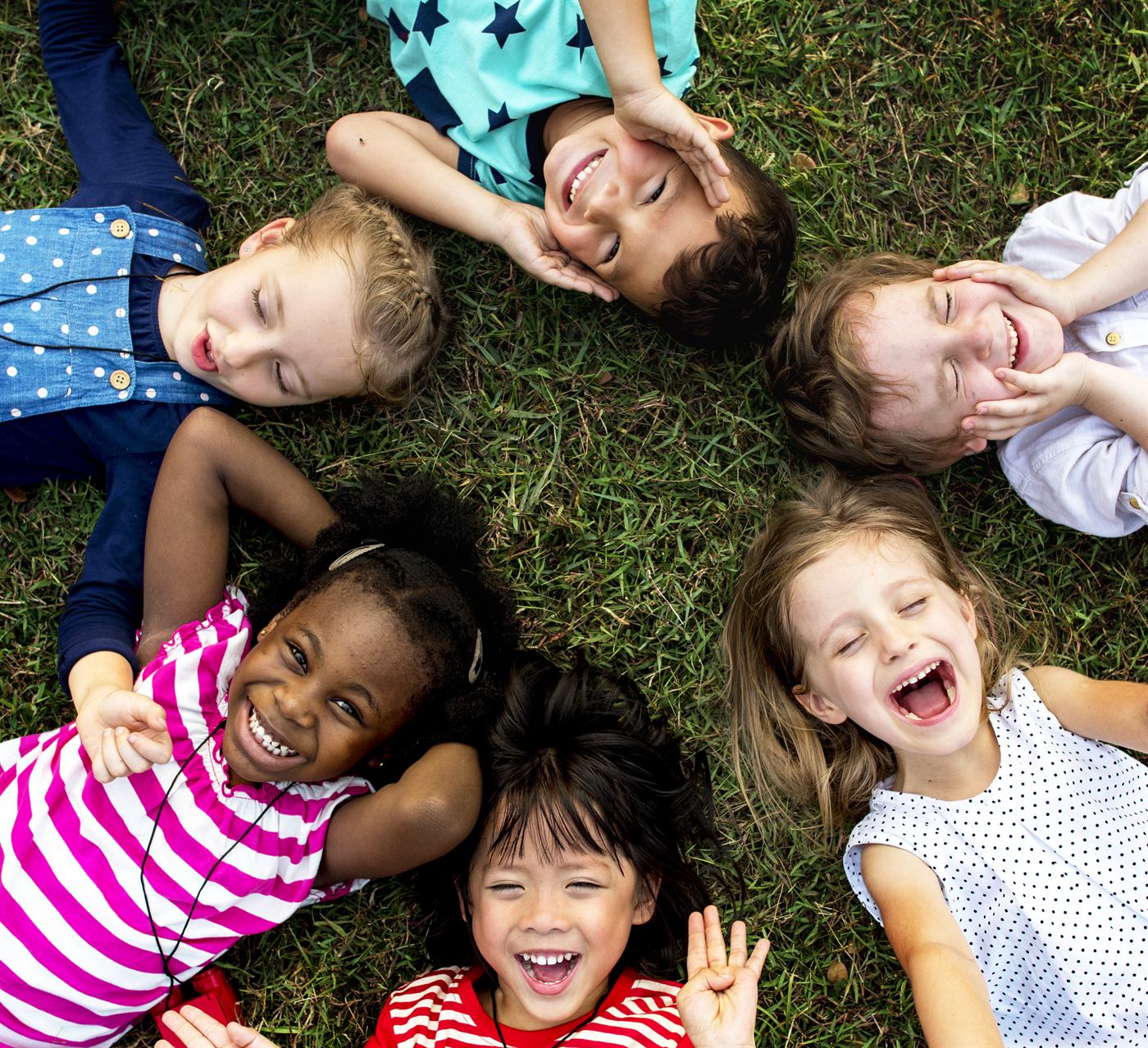 A group of happy children lying in a circle on the grass